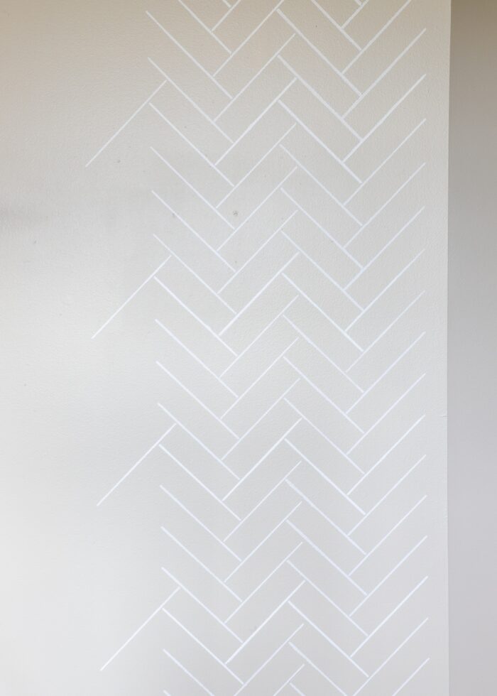 Beige wall stenciled in a white herringbone tile pattern