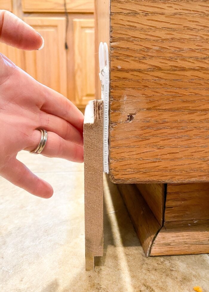 Hands holding shiplap onto island with Command Strips
