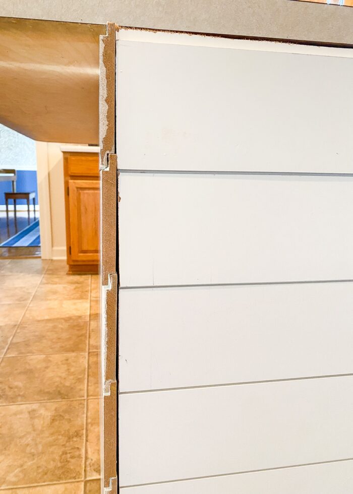 Corner of kitchen island covered in white shiplap boards