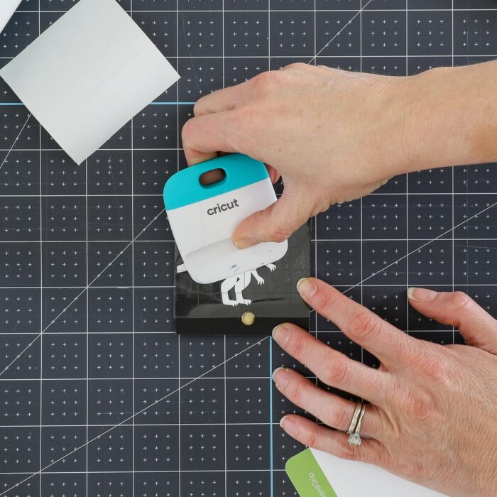 Hands using scraper on white vinyl toy bin label