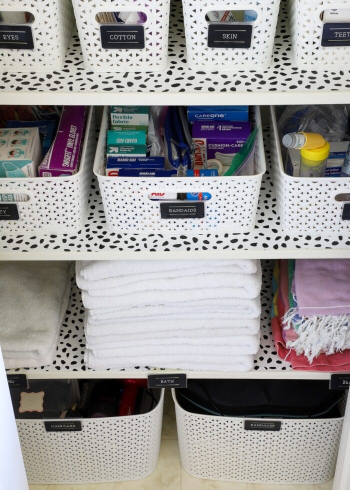 Bathroom closet shelves with white baskets and folded towels