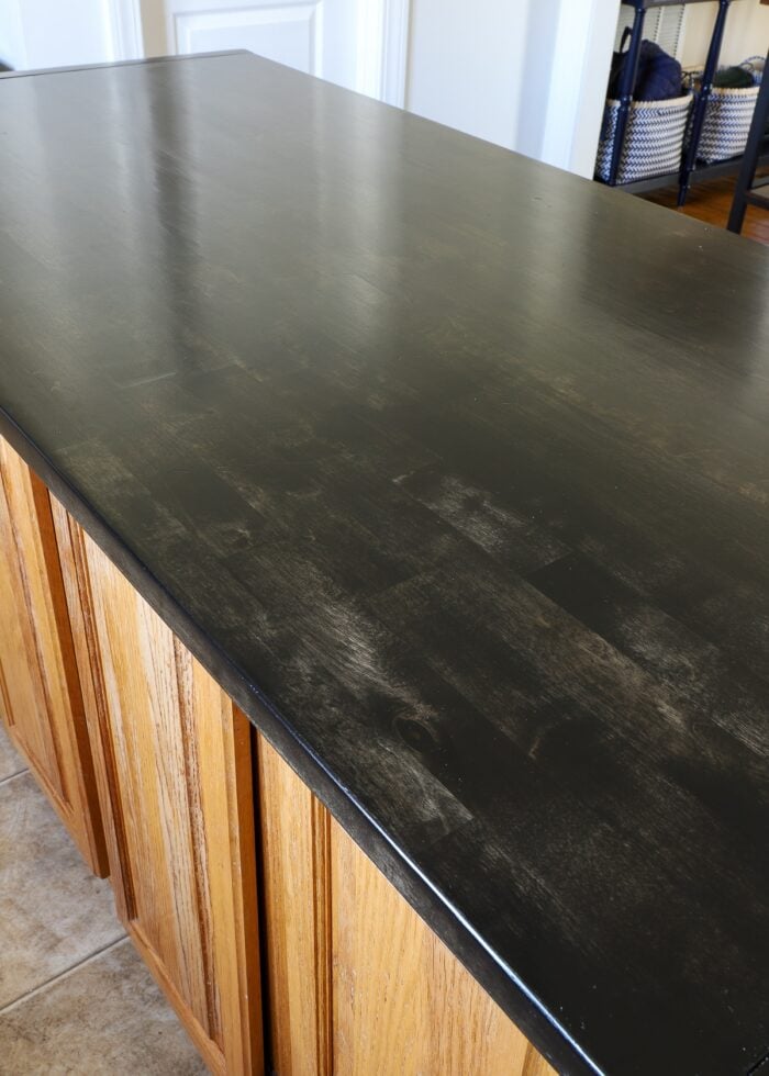 Ebony-stained butcher block island countertop with oak base cabinets
