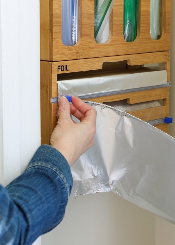 Hand cutting away tin foil from hanging organizer inside a pantry