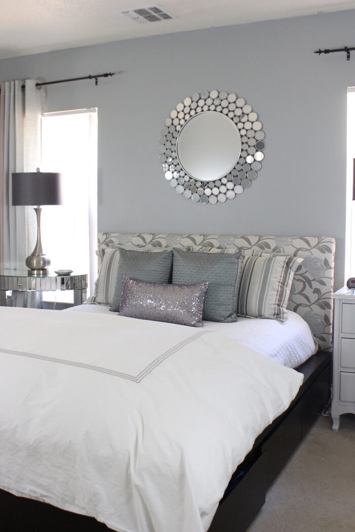 Grey master bedroom with floral headboard and a mirror above the bed
