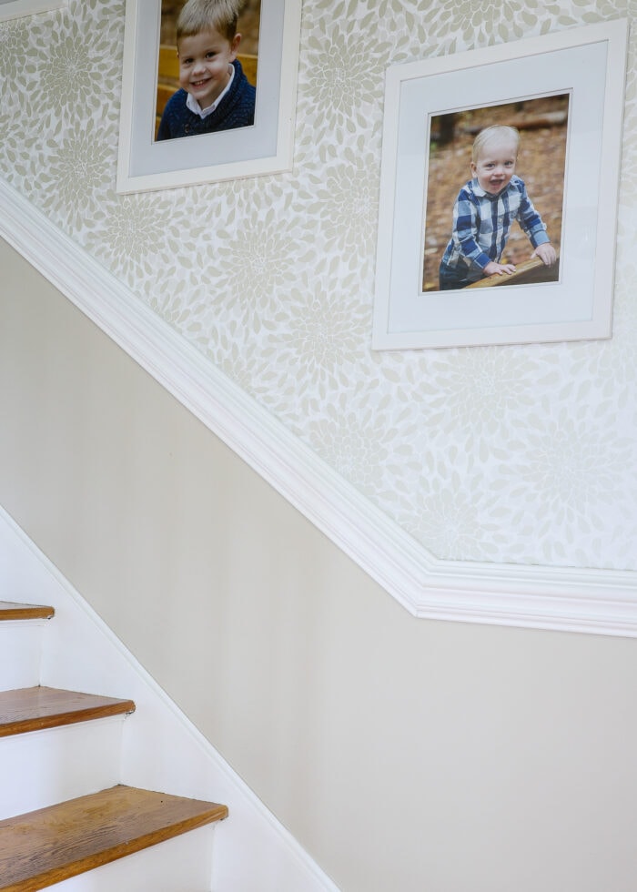 Stairwell with painted lower wall, white trim, and floral wallpaper