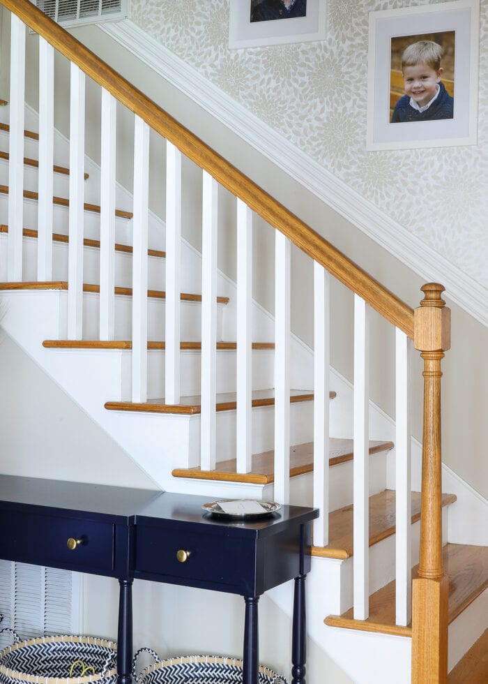 Stairwell with painted lower wall, white trim, and floral wallpaper