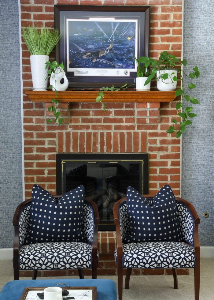 Red brick fireplace with blue wallpaper and art