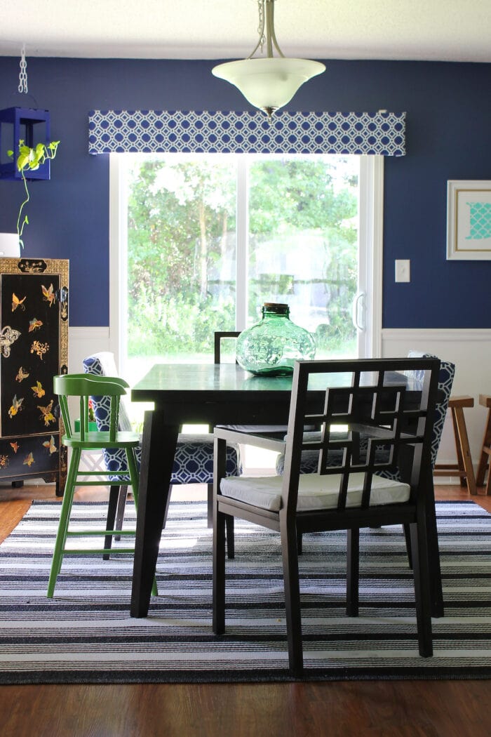Blue and white dining room with striped rug and black chairs