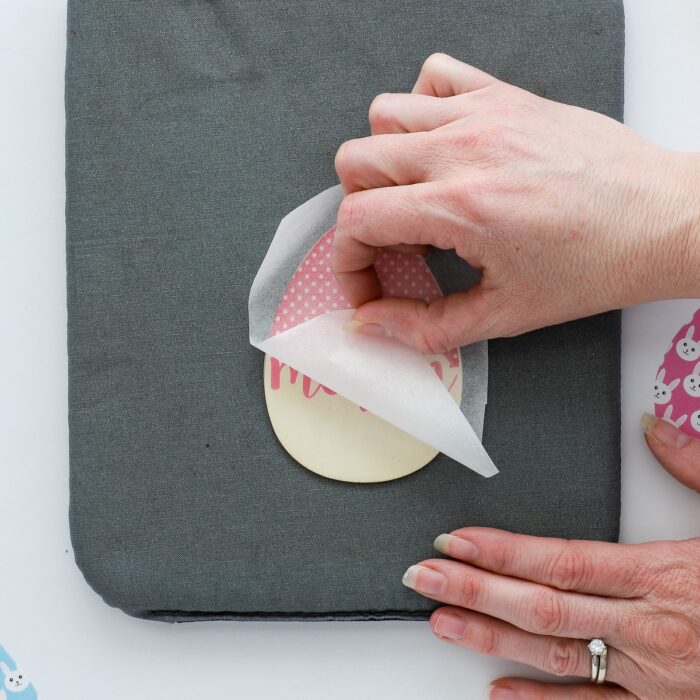 Hand peeling away parchment paper from wooden Easter basket tag