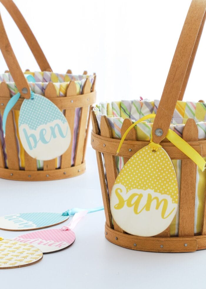 Yellow and blue egg-shaped wooden name tags tied onto brown Easter baskets