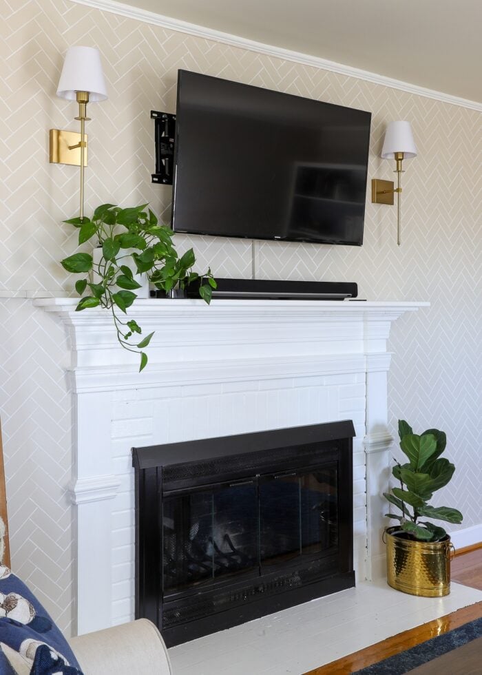 Brass wireless wall sconces mounted above a fireplace in a rental