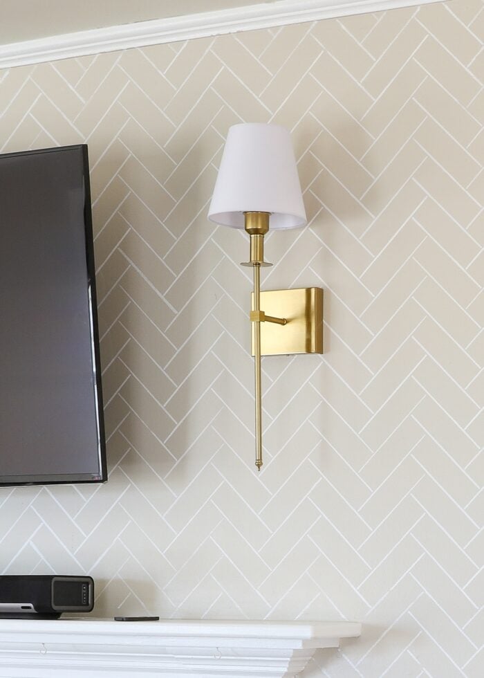 Brass battery-operated wall sconce next to wall-mounted TV