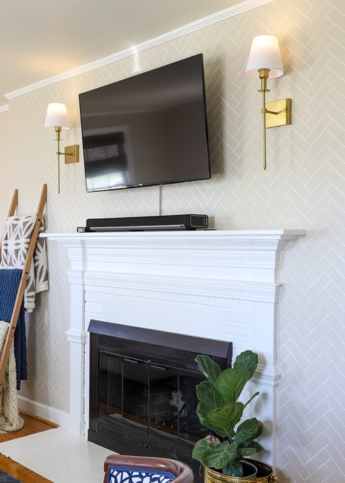 Brass wall sconces on both sides of a wall-mounted TV turned on