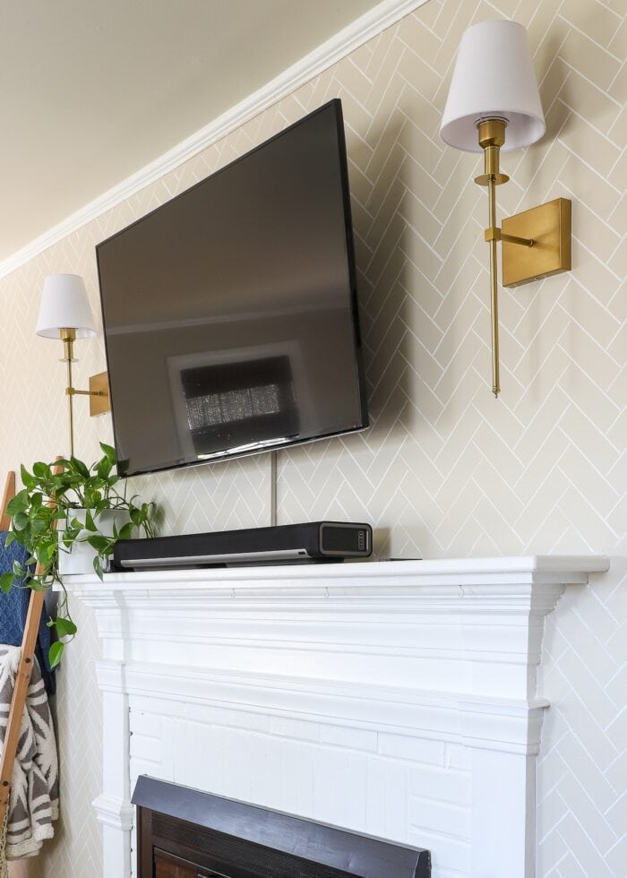 Renter friendly brass wall sconces on both sides of a wall-mounted TV