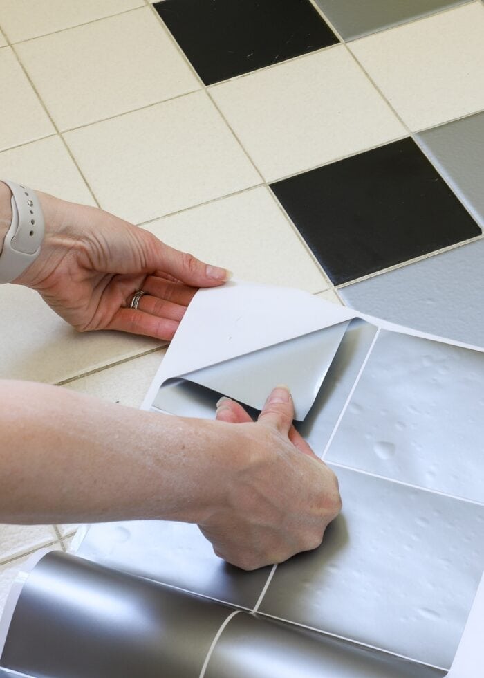 Hand peeling up a bathroom tile sticker