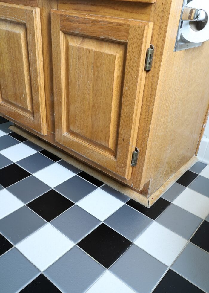 Black and white buffalo plaid tile floors made with bathroom tile stickers underneath a pine vanity