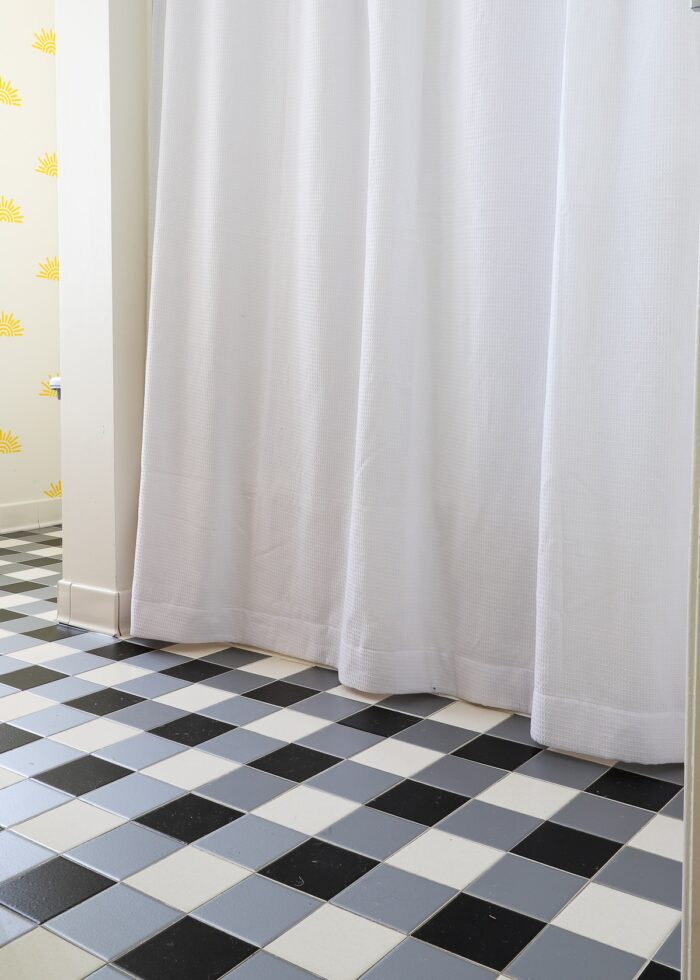 Black and white buffalo plaid tile floors made with bathroom tile stickers next to a white shower curtain