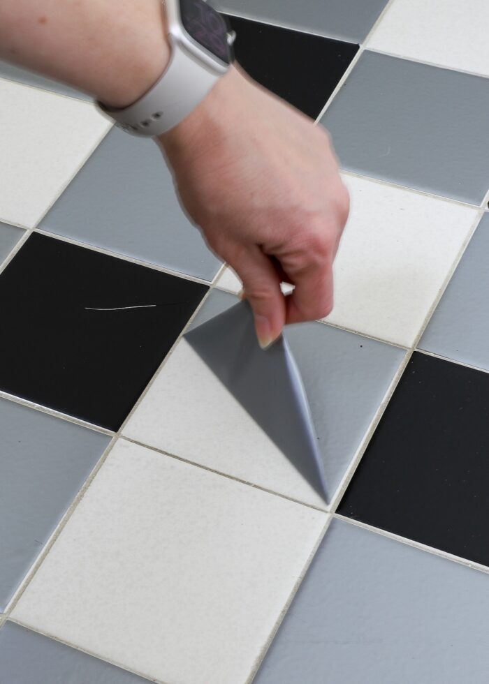 Hand peeling up a bathroom tile sticker