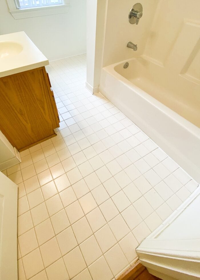 Beige tile floor in a white builder basic bathroom