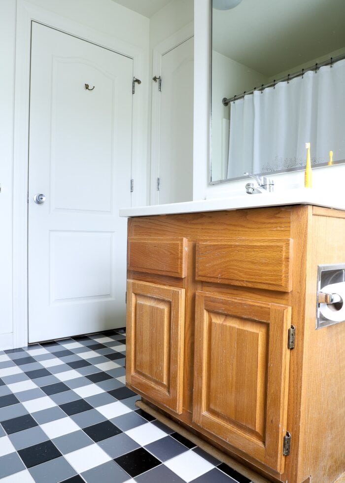 Black and white buffalo plaid tile floors made with bathroom vinyl tile stickers shown alongside a pine vanity