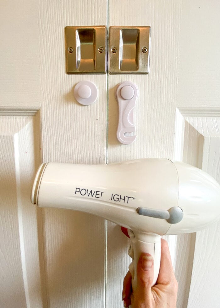 Hair dryer shown alongside adhesive hooks on white doors