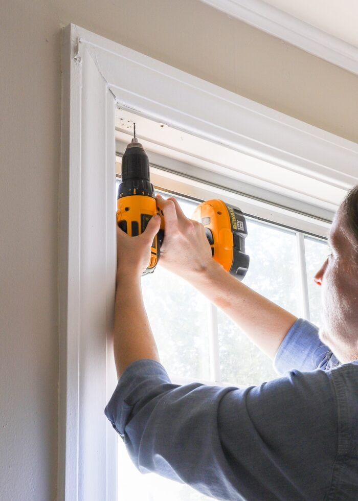 Megan using a drill inside a window frame to install cordless blinds