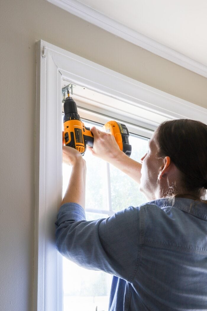 Megan using a screwdriver inside a window frame to install cordless blinds