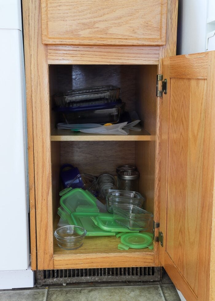 Oak kitchen cabinet loaded with mismatched food storage containers