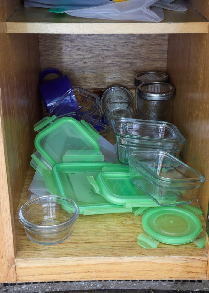 Oak kitchen cabinet loaded with mismatched food storage containers