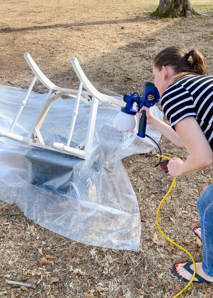 Megan spraying dining chairs with a paint sprayer
