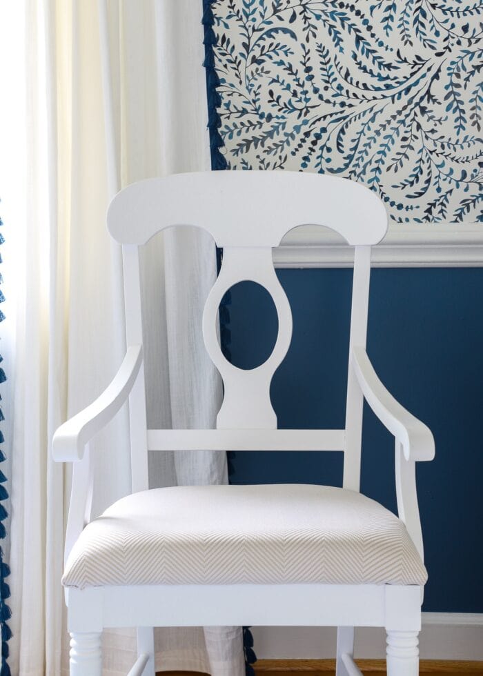 Back of white dining room chair against a blue wall