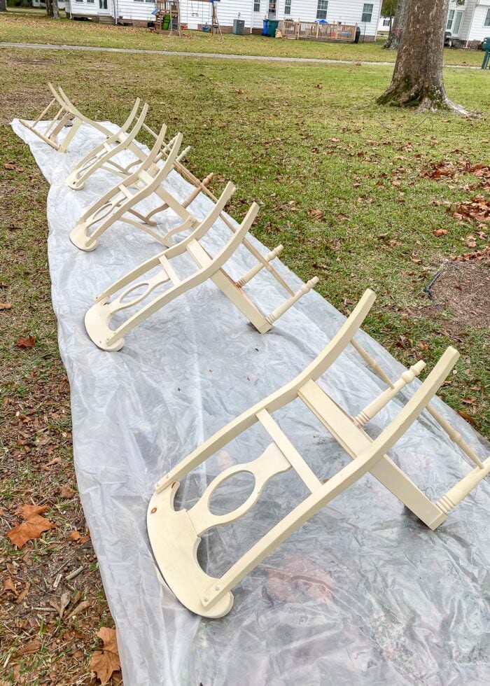Ivory dining chairs flipped over on a tarp ready for painting