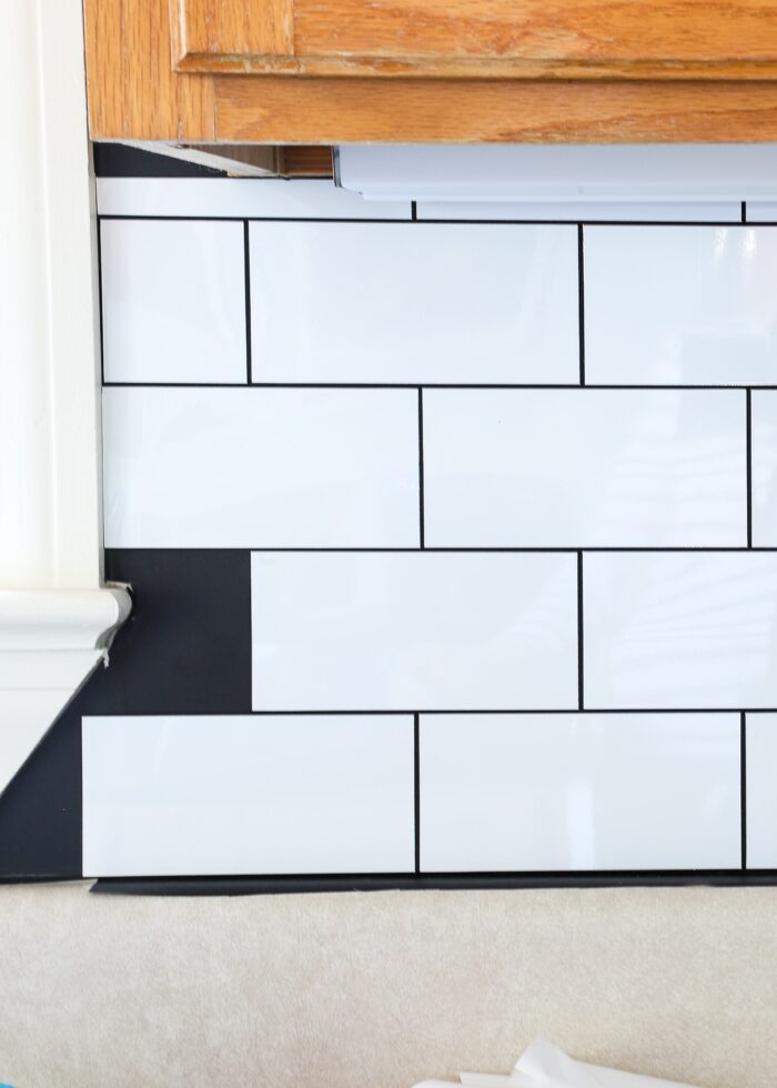 White peel and stick subway tile installed on backsplash on top of black contact paper