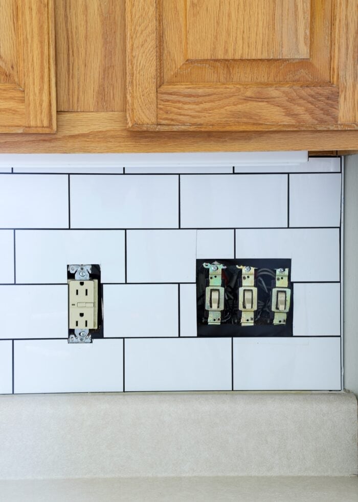 Completed subway tile backsplash on wall before outlet covers are replaced