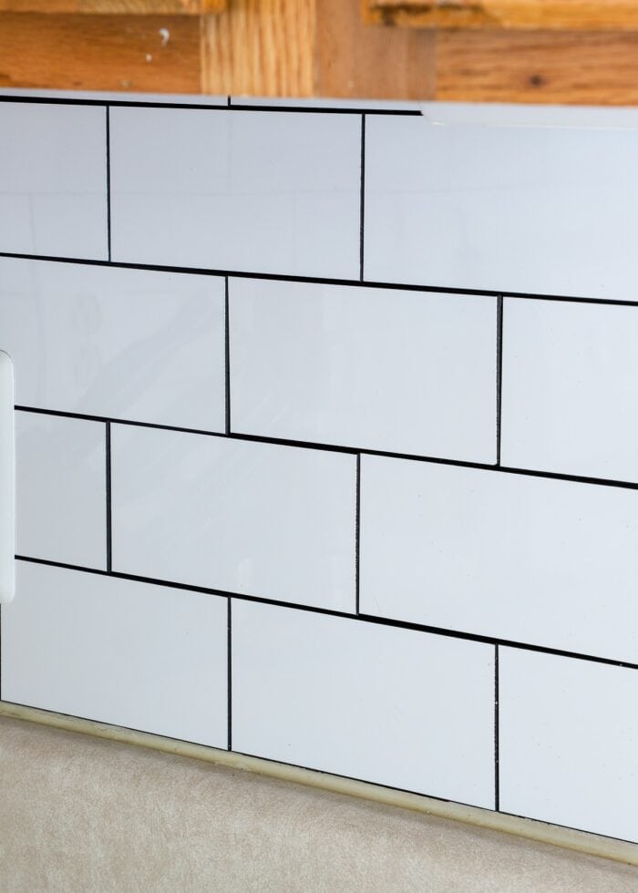Peel and stick white subway tile on backsplash below oak cabinets