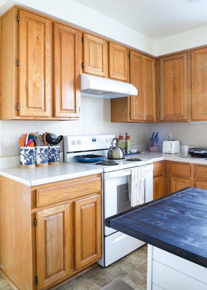Builder-grade rental kitchen with honey oak cabinets and laminate backsplash