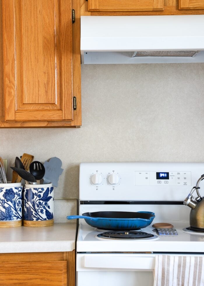 Laminate backsplash in builder-grade rental kitchen with honey oak cabinets