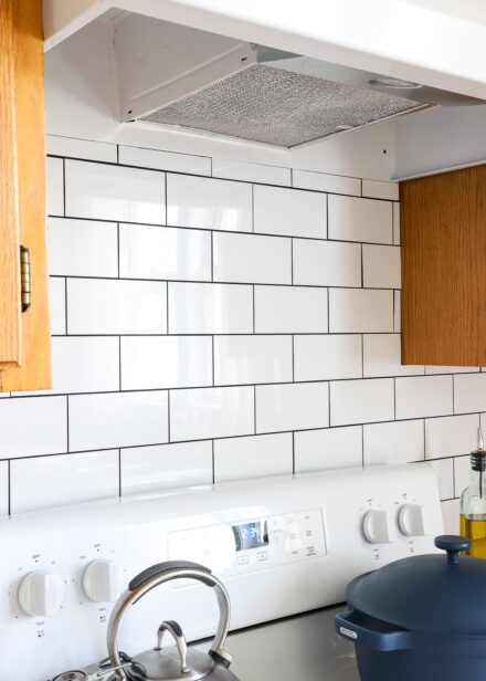 Peel and stick white subway tile on backsplash above stove
