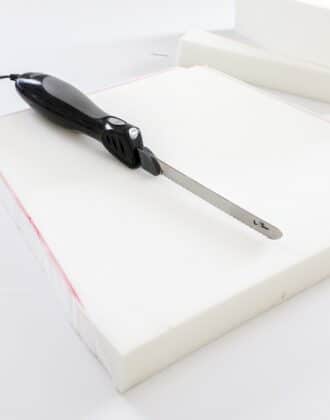 Electronic cutting knife shown on top of newly cut foam cushion