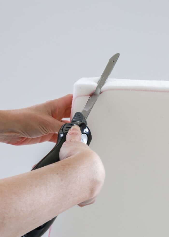Hands using electronic cutting knife to carve upholstery foam