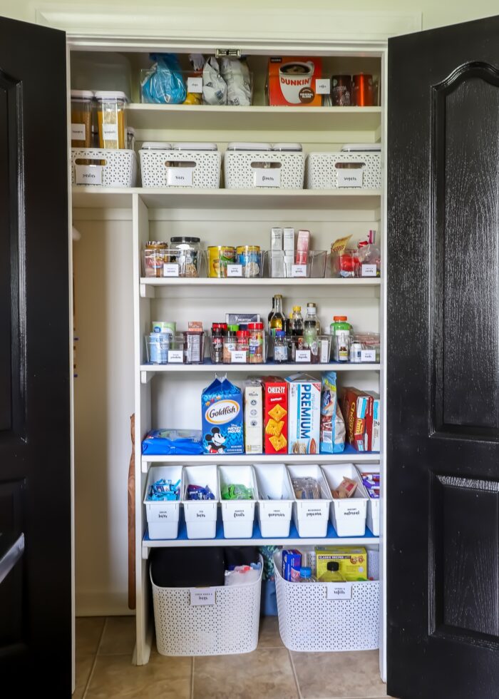 Organized pantry with black doors and white bins and baskets