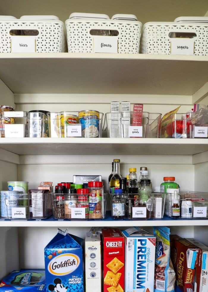 Organized pantry shelves using clear and white bins and baskets