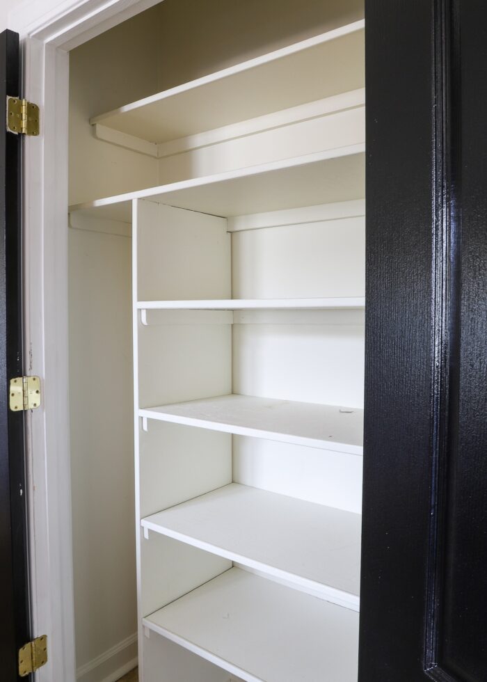 Empty pantry with wooden shelves and black doors