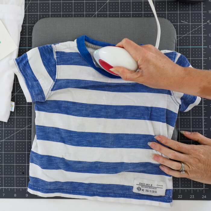 Hand using EasyPress Mini to attach iron on label to boy's t-shirt
