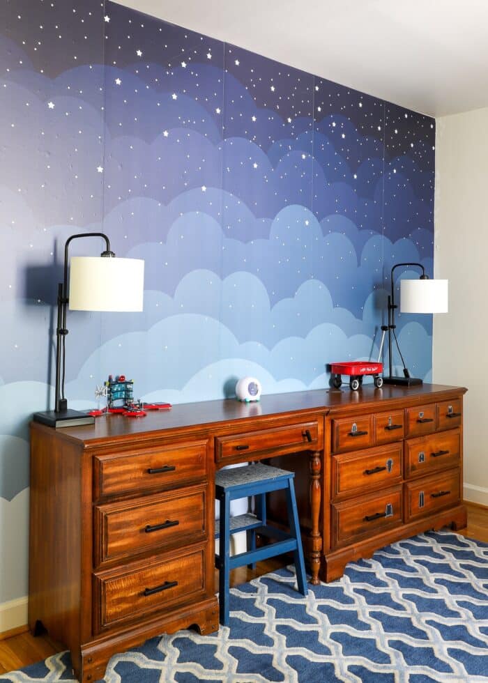 Wooden dressers up against a blue cloud wall mural