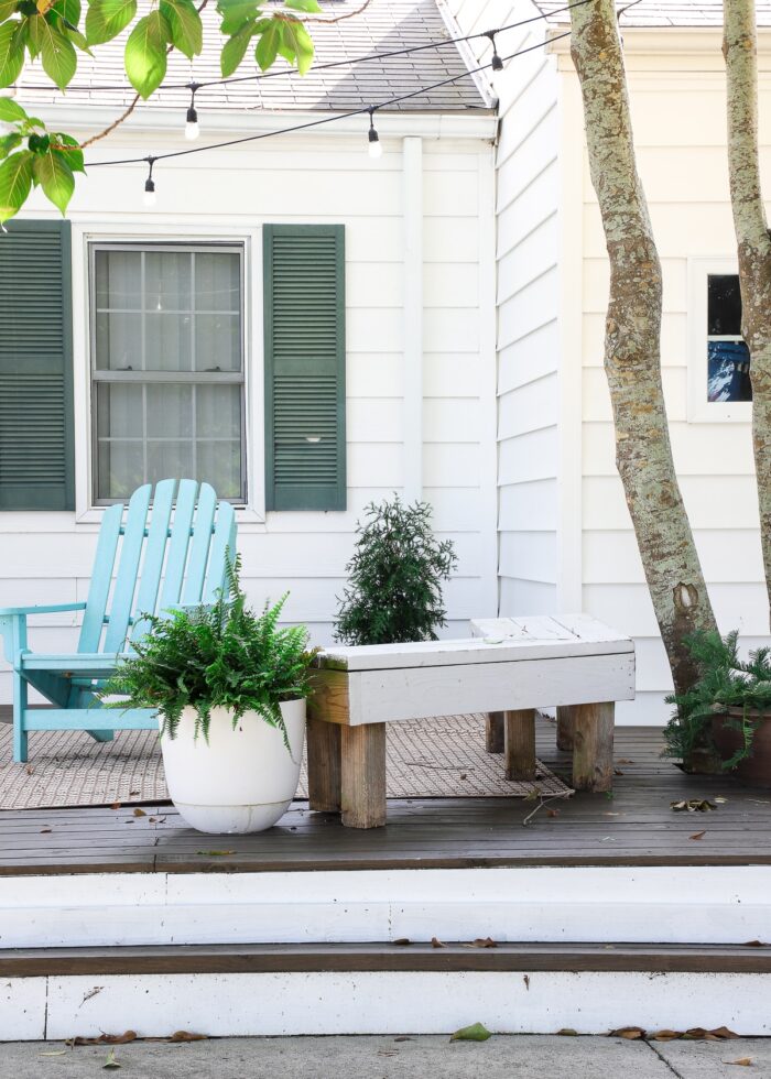 Turquoise chair, wooden garden bench, and plants on a wood and white deck.