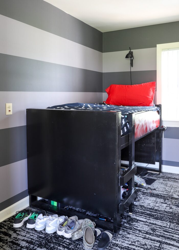 Tween bedroom with grey striped walls and large black loft bed