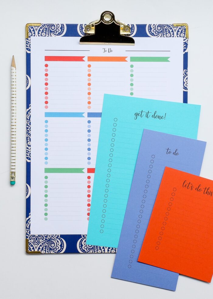 A multi-color printable to do list on a blue clipboard with smaller to do lists on colored cardstock next to it