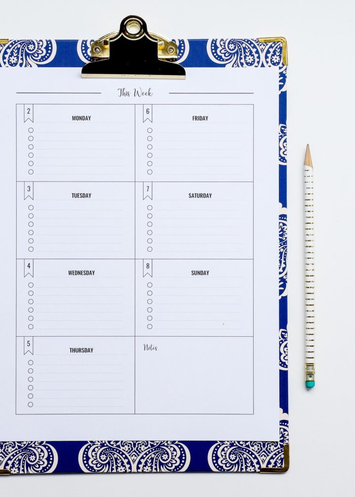 A weekly checklist printed in black and white on a blue clipboard
