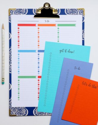 A multi-color printable to do list on a blue clipboard with smaller to do lists on colored cardstock next to it